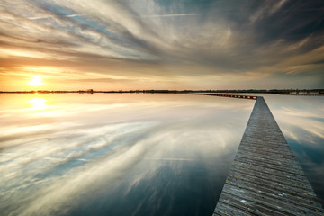 wooden walk way on big lake during sundown
