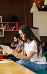 Beautiful student girl working with tablet computer sitting in coworking cafe office