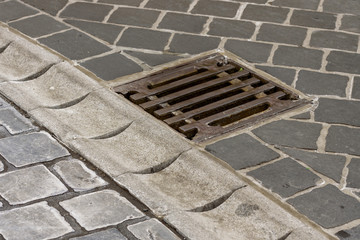 a reservoir for collecting water after a rain and a sewer grid along the road