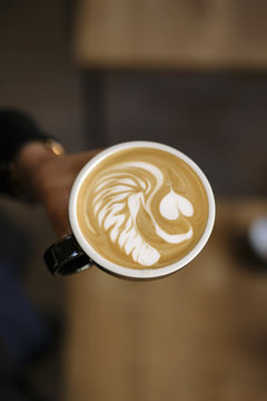 Close-up of Hand Holding Coffee Cup with Intricate Lion Latte Art