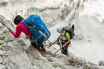 Climbers tackling via ferrata metalic ladder.
