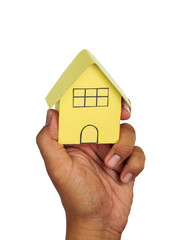 Man's hand holding Yellow house on white background.