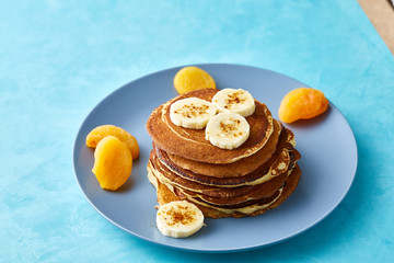 Pile of homemade pancakes with honey and walnuts on rustic wooden background, selective focus