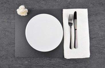 Weiße Rose und Gedeck auf Schiefer