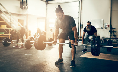 Fit young man lifting weights in a gym