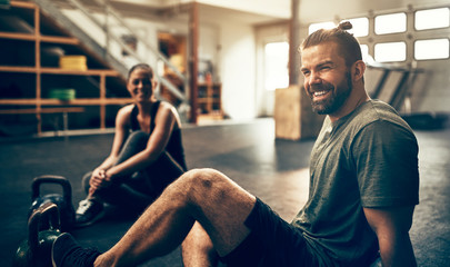 Smiling people relaxing on a gym floor after working out
