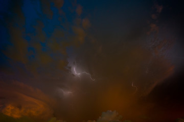 Stroke of lightning with storm clouds and golden sunset light