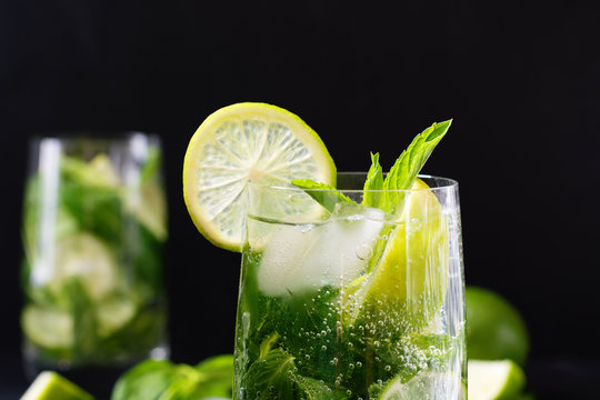 Mojito cocktail in glass on black table. Low key photo. Close up.
