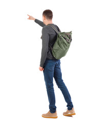Back view of a man with a green backpack pointing forward.
