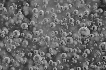 Black-and-white background with big and small grey bubbles inside a gray liquid.