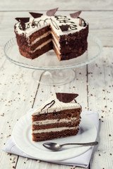 dark chocolate vegan cake with cream on wooden background