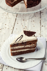 dark chocolate vegan cake with cream on wooden background