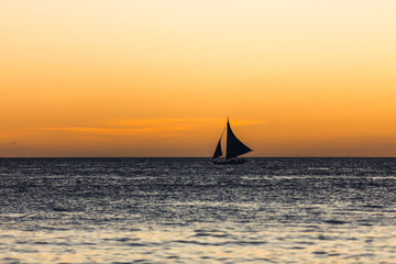 Obraz na płótnie Canvas One outrigger sailboat on the horizon