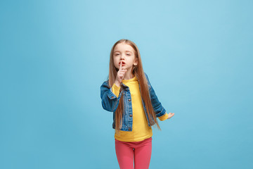 The young teen girl whispering a secret behind her hand over blue background