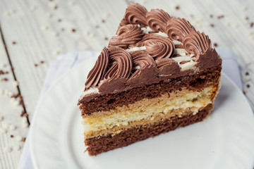 dark chocolate vegan cake with cream and caramel on wooden background