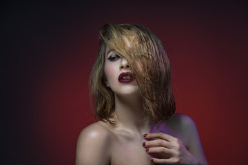 Beautiful vamp makeup sexy woman with red lipstick red background in dramatic light.