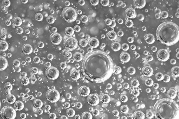 Black-and-white background with big and small grey bubbles inside a gray liquid.