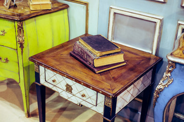 Rich and expensive retro furniture and old books lying on it - photo with selective focus
