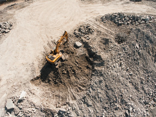 Aerial drone view of excavator loading the tipper truck at the construction site, open pit mine, extractive industry
