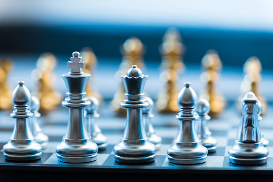 silver chess pieces on a silver chessboard, business strategy concept