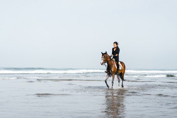 Fototapeta na wymiar female equestrian riding horse in wavy water
