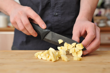 Man slices a banana with a large knife on a wooden board