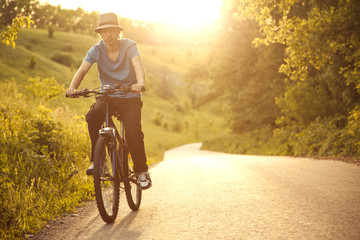 teenager riding a bicycle on the road summer sunlit