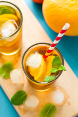 Glasses of iced tea with lemon slices and mint on turquoise wooden background