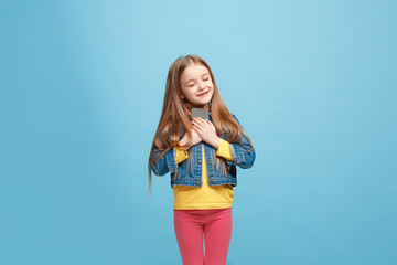 The happy teen girl standing and smiling against blue background.