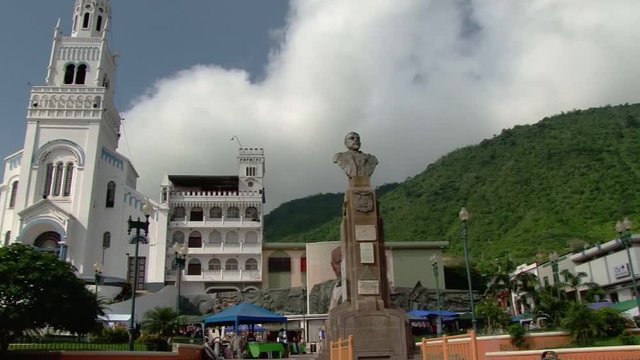 Pan across square from bust of Eloy Alfaro to church in Montecristi