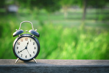 Black alarm clock on nature background with copy space
