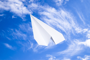 White paper airplane in a blue sky with clouds. The message symbol in the messenger