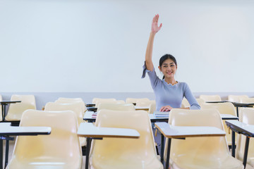 Young woman student raising hands in a classroom showing ready answer. concept of education.