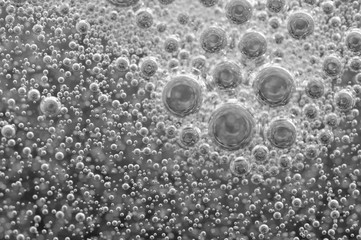 Black-and-white background with big and small grey bubbles inside a gray liquid.