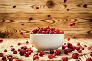 red strawberries in bowl on a wooden background