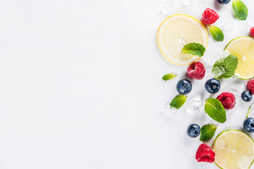 Healthy organic summer food and drink concept, selection of fresh fruit and berries, lime lemon raspberry blueberry pattern on white background copy space above top view