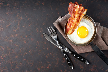 Fried bacon and eggs breakfast. Top view, isolated on black background.