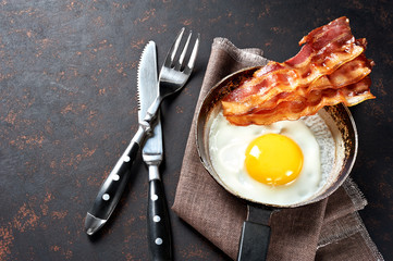 Fried bacon and eggs breakfast. Top view, isolated on black background.