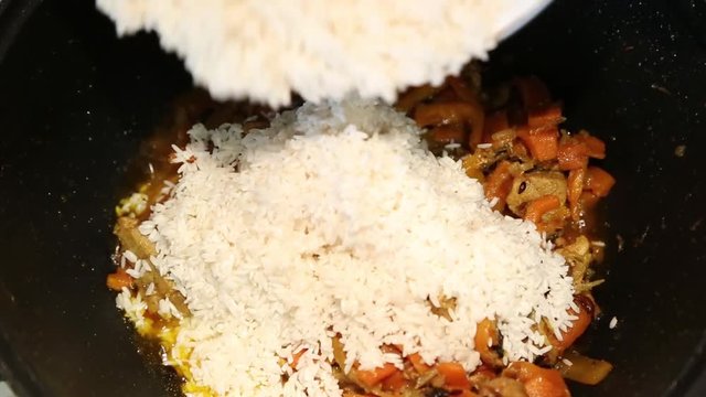 Preparation of rice dishes - pilaf from Uzbekistan. In the pan with fried meat and spices pour rice.
