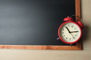 Red vintage alarm clocks over the blackboard on wooden table