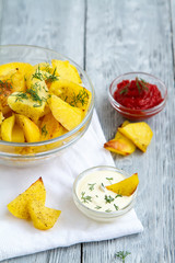 delicious fried potato slices with two sauces on wooden grey background