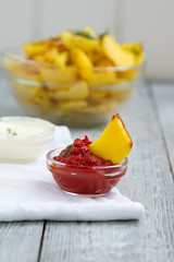 delicious fried potato slices with two sauces on wooden grey background