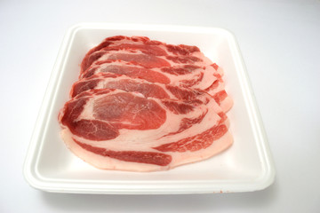 食品トレーに入った豚ロース肉　白背景　コピースペースあり	