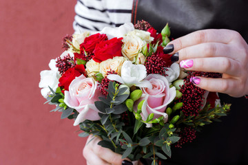 Young florist holding wedding bouquet of roses. Fashion modern bouquet of different flowers.