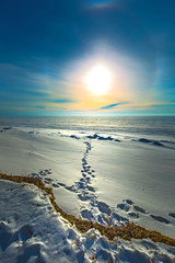 The setting winter sun and solar halo over the frozen river. Siberia