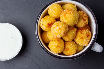 Spicy cheese balls with juicy chicken meat inside. Beer snack. With sauce. On a black plate. View from above, close-up