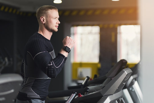 Young man in gym running on treadmill