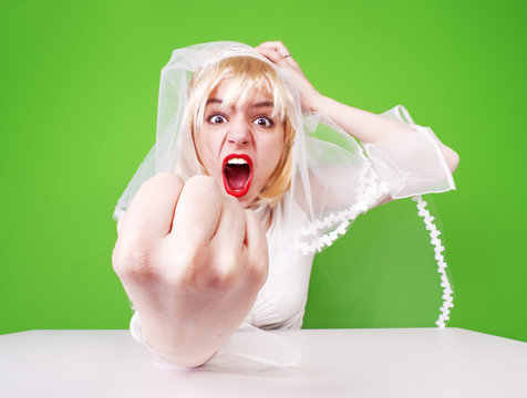 Angry Bride. Beautiful, Pretty, Furious Woman In Wedding Dress Girl, Bride, Lady Shows Her Hand With A Fist On A Green Background