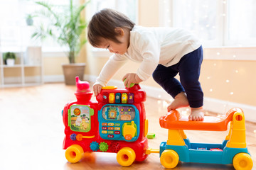 Happy toddler boy playing with toys in his house