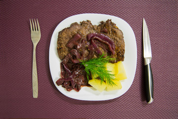 Steak with boiled vegetables, potatoes and violet onions. Served table.